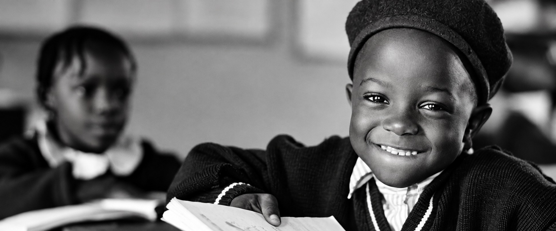 Enhanced black-and-white photograph of a smiling learner with an open book